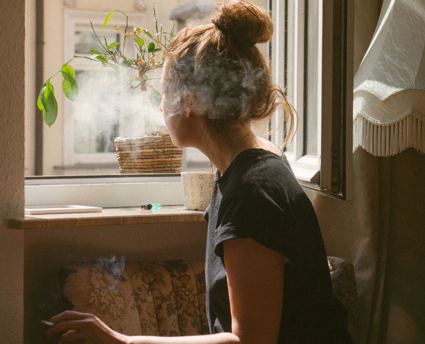 Femme à la fenêtre en train de fumer